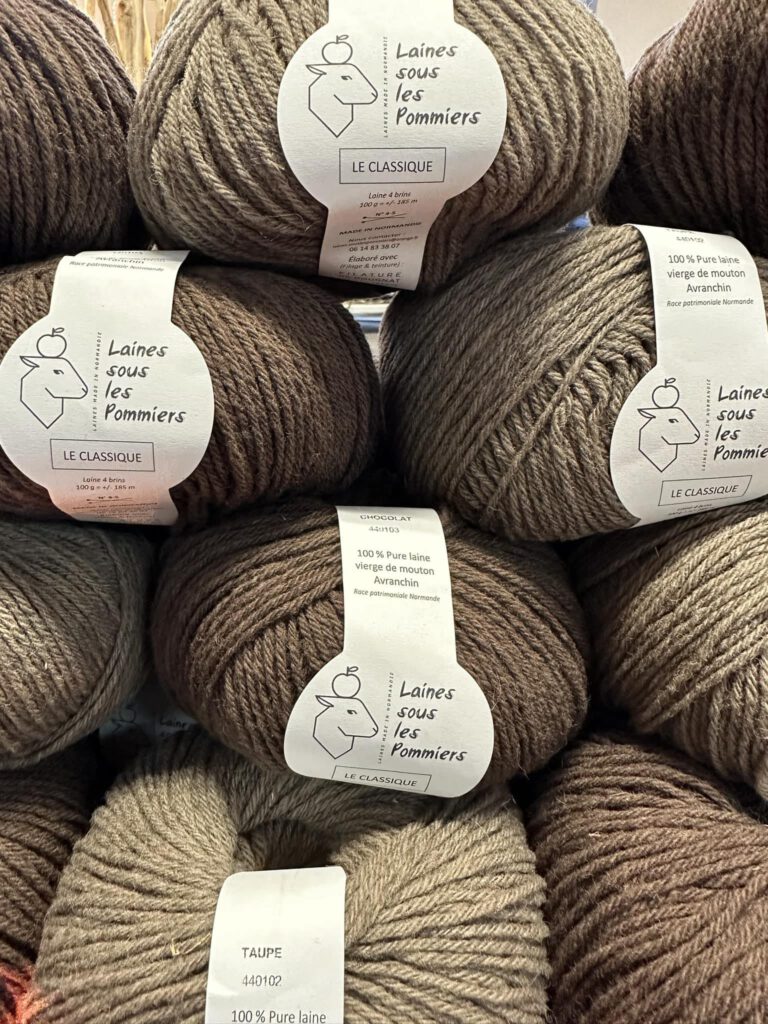 Pelotes de laine de mouton de la marque "Laines sous les Pommiers", mettant en avant des couleurs naturelles et durables.
