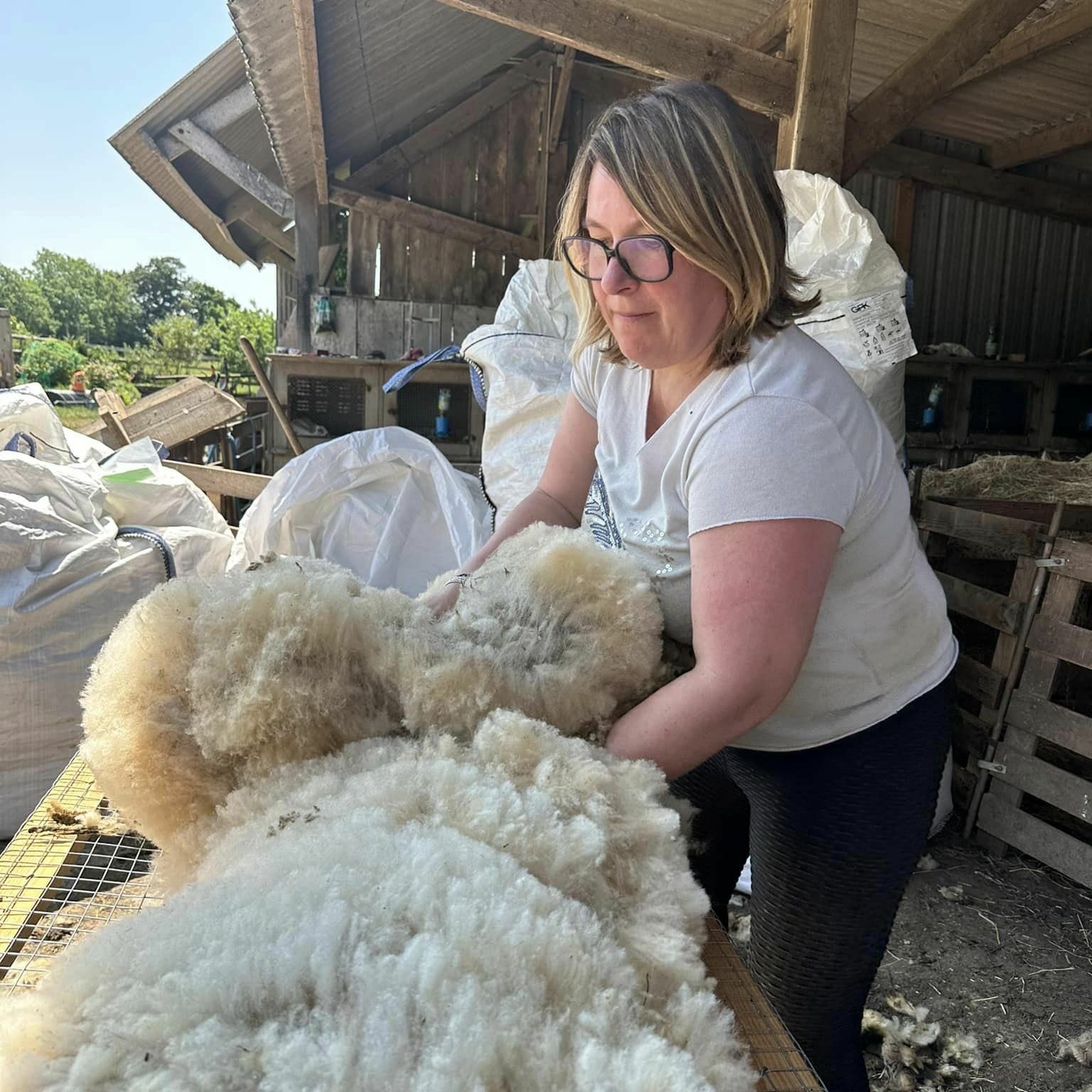 Femme manipulant de la laine de mouton dans un environnement de production durable.