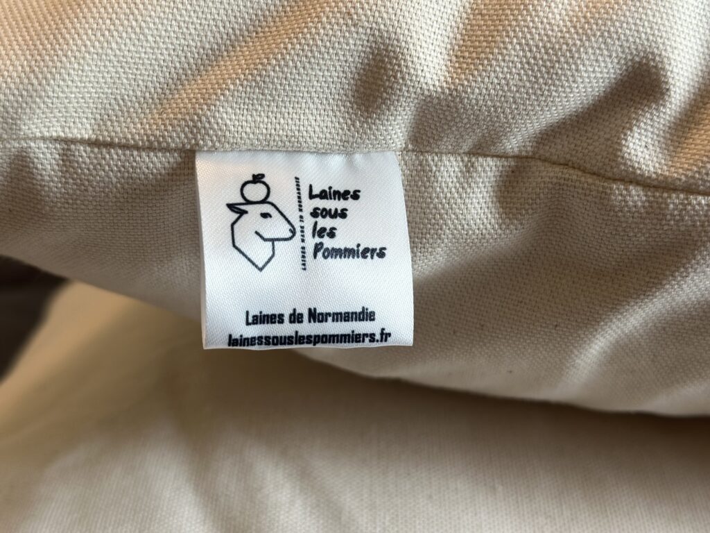 Étiquette de la marque "Laines sous les Pommiers" sur un produit en laine, soulignant la durabilité et l'origine normande.