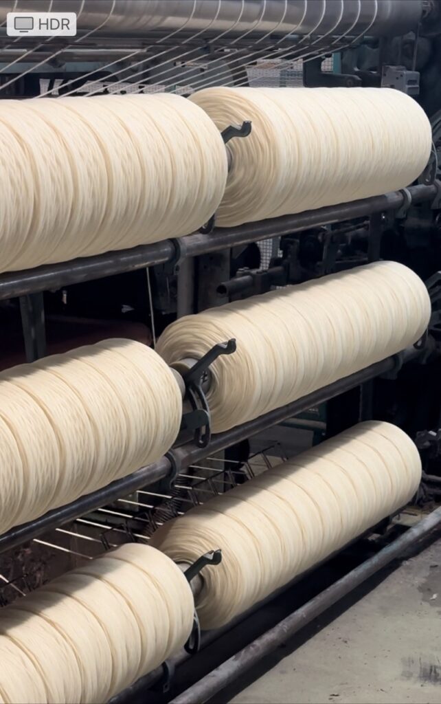 Bobines de laine blanche sur un rouleau, processus de transformation à l'entreprise Laines sous les Pommiers.