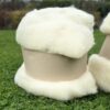 Deux rouleaux de laine de mouton naturelle sur un fond d'herbe, symbolisant la durabilité de l'entreprise "Laines sous les Pommiers".
