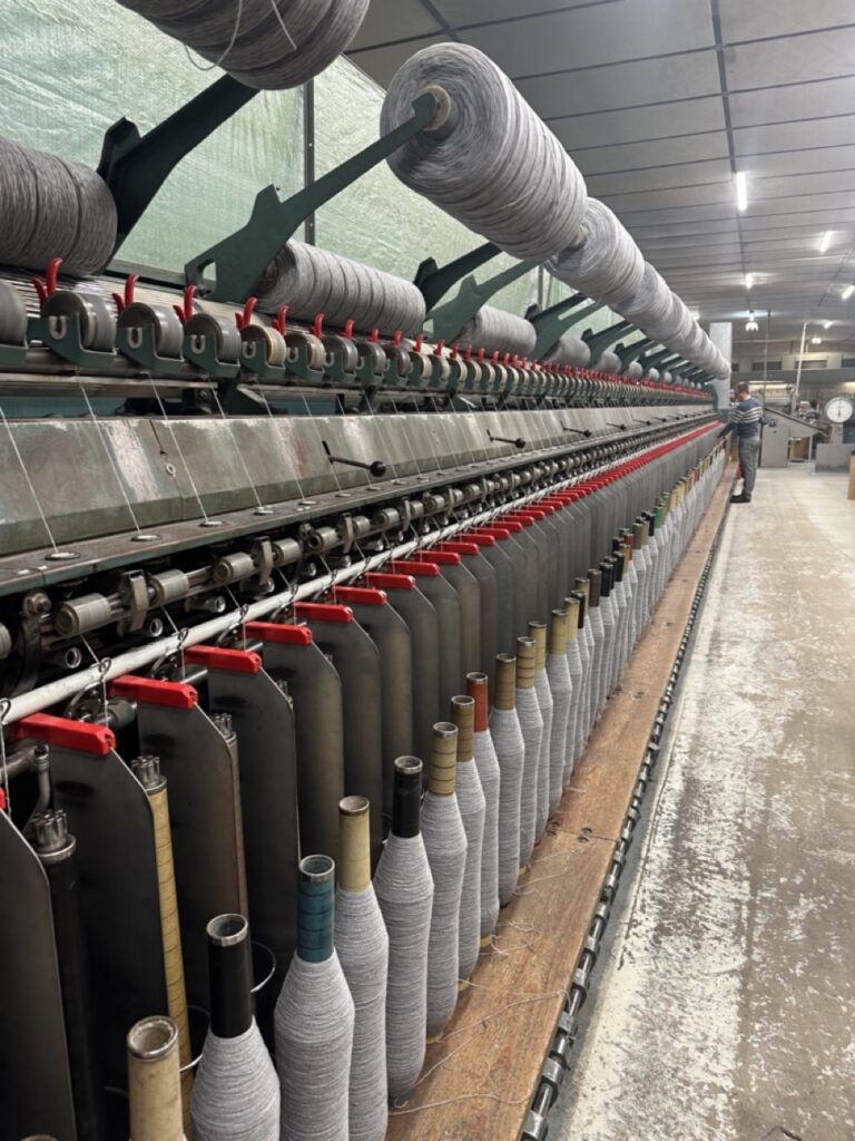 Machine de filage avec bobines de laine en cours de production dans un atelier respectueux de l'environnement.