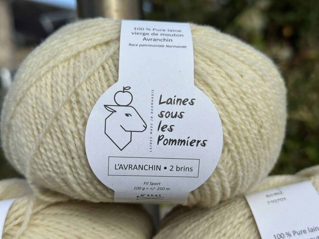 Pelote de laine vierge 100 % Avranchin, coloris écru, label "Laines sous les Pommiers", mise en avant de la production locale normande.