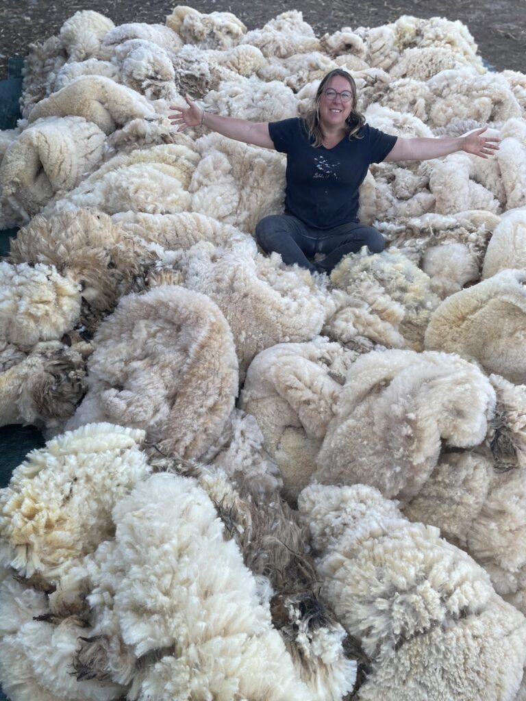 Femme assise au milieu de grandes pelotes de laine, représentant l'artisanat local et la valorisation de la laine normande.